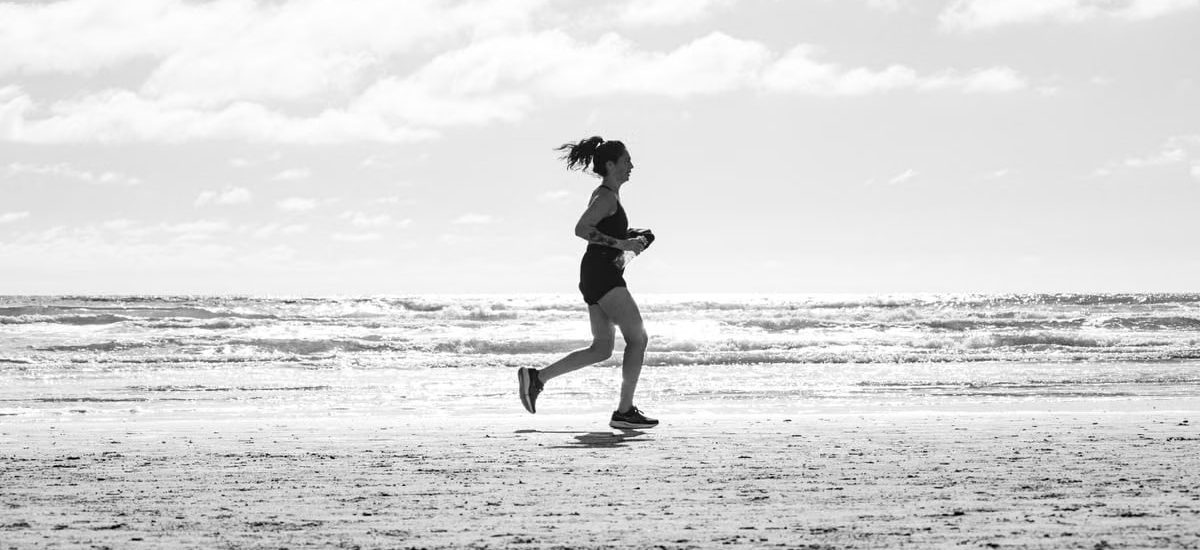 A woman jogging on La Lucila del Mar beach, Argentina in a monochrome setting. Capturing fitness and freedom.